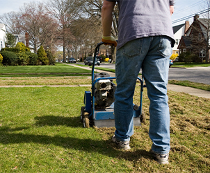 A man performing commercial lawn maintenance using a machine to mow grass.